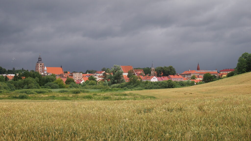 Widok na wieś z pola z burzowym niebem.
