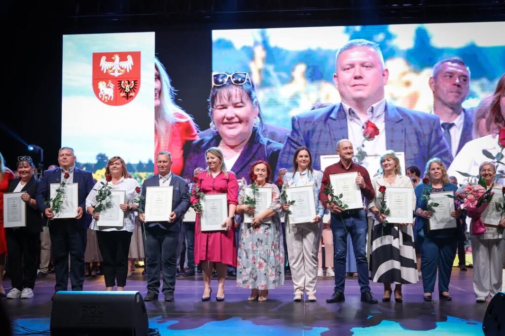 Grupa nagrodzonych osób z dyplomami na scenie.