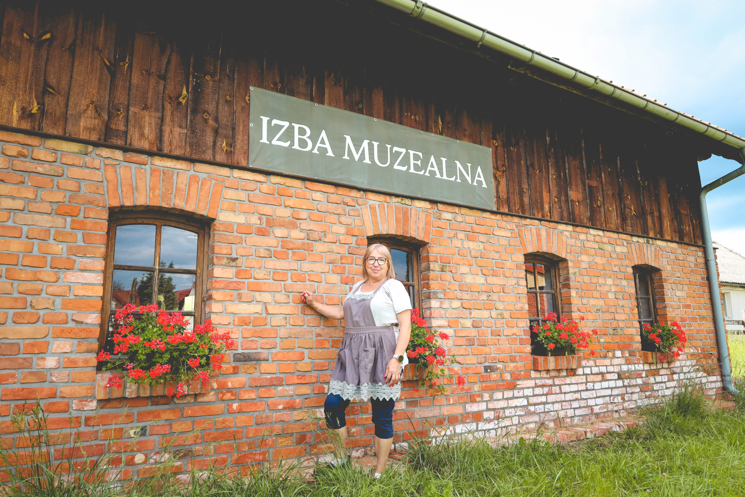 Kobieta stoi przed murowanym budynkiem z czerwonej cegły.