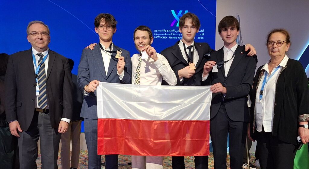 Grupa ludzi trzymających flagę Polski i medale.