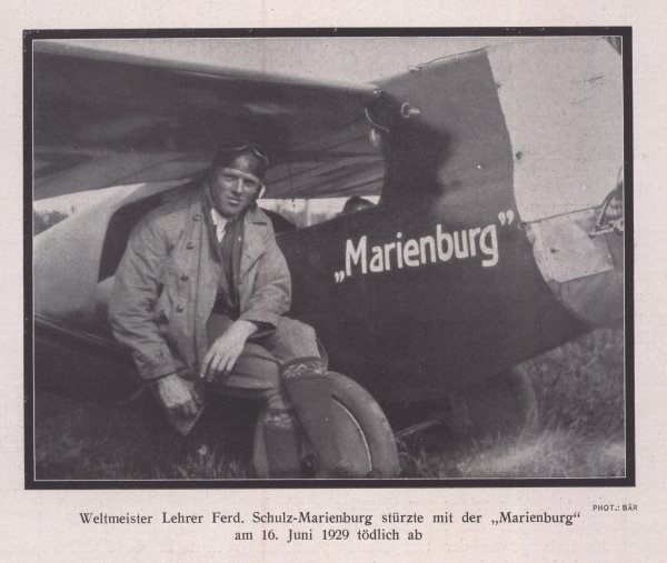 Mężczyzna siedzący obok samolotu z napisem "Marienburg".