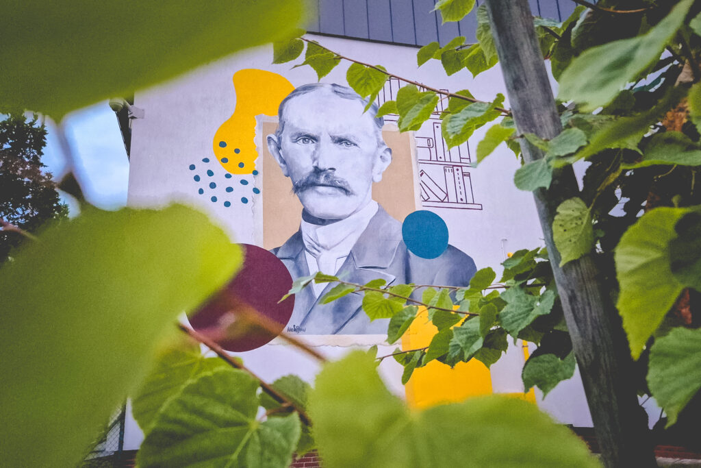 Mural przedstawiający mężczyznę zza liści.