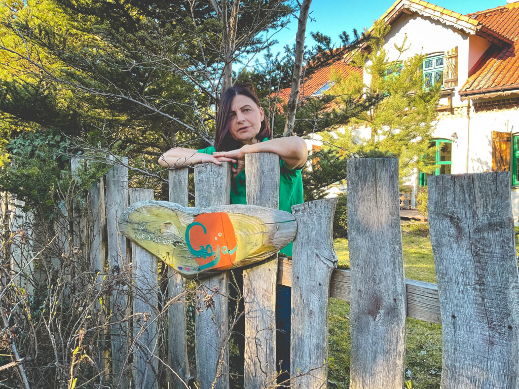 Kobieta opierająca się o drewniane płot z sercem.