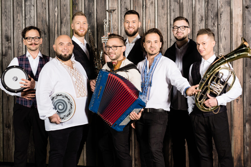 Grupa muzyków trzymających instrumenty w tradycyjnych strojach.