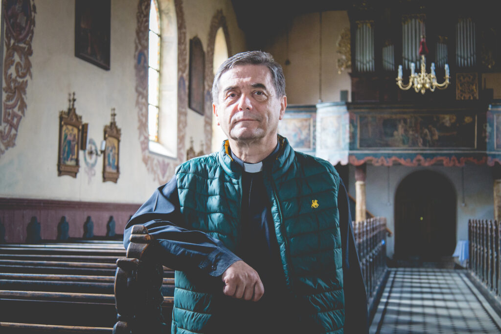 Mężczyzna w zielonej kamizelce stojący w kościele.