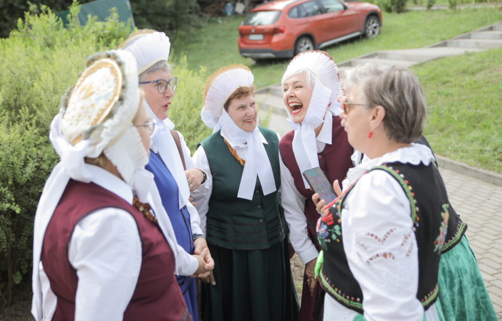 Grupa kobiet w tradycyjnych strojach ludowych rozmawia i się śmieje.