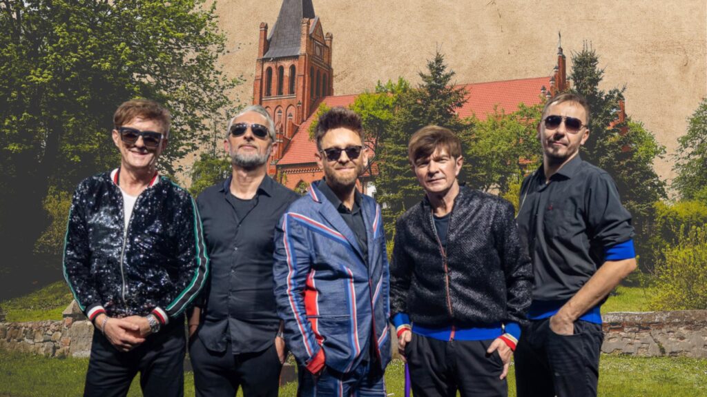 Grupa mężczyzn w eleganckich ubraniach przed budynkiem.