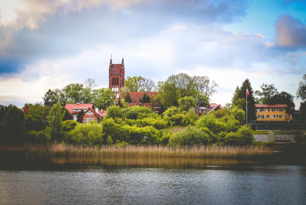 Widok na malowniczą wieś nad jeziorem z kościołem i drzewami.