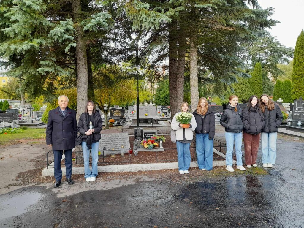 Grupa osób na cmentarzu z kwiatami