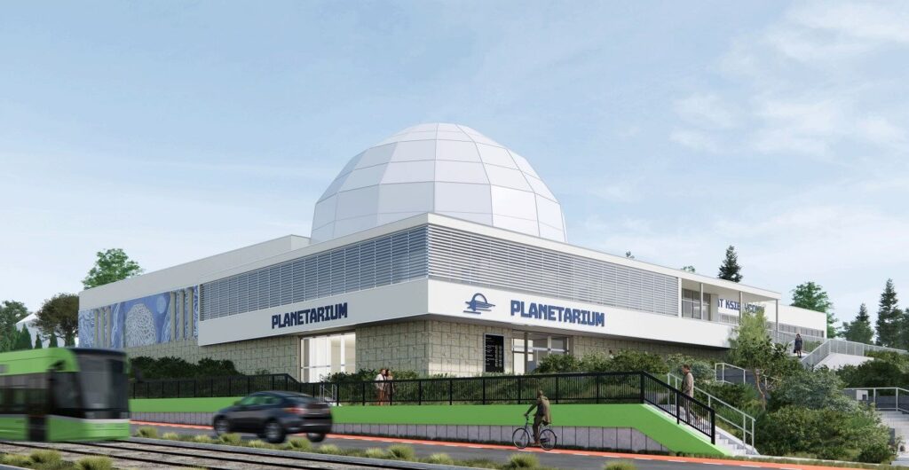 Nowoczesne planetarium z kopułą i zielonym otoczeniem.