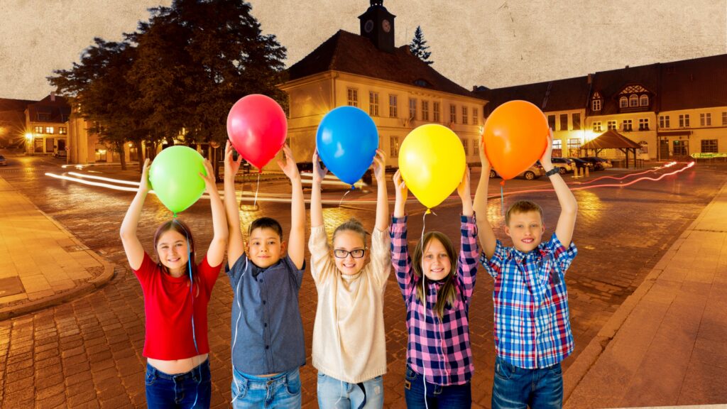 Dzieci trzymające balony na ulicy.