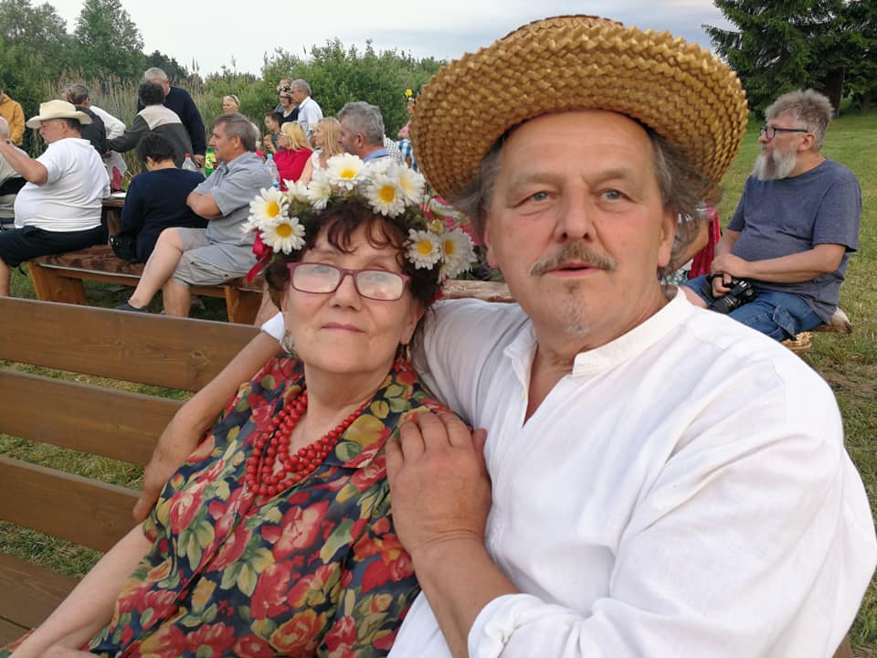 Para ludzi w tradycyjnych strojach na tle spotkania.