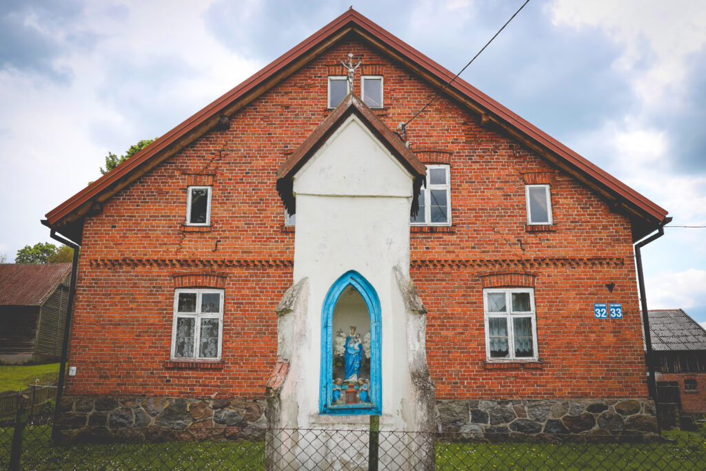 Czerwony dom z figurą religijną.