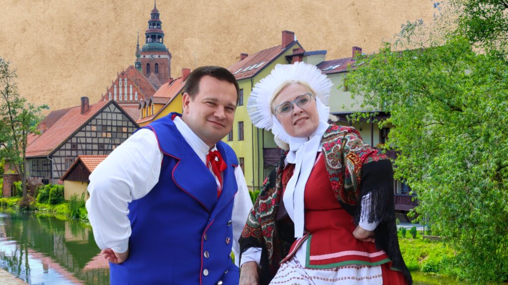 Para w tradycyjnych strojach ludowych na tle malowniczej architektury.