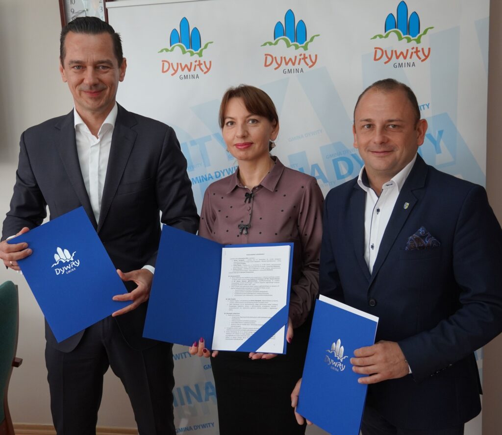 Trzy osoby prezentujące umowy w biurze.