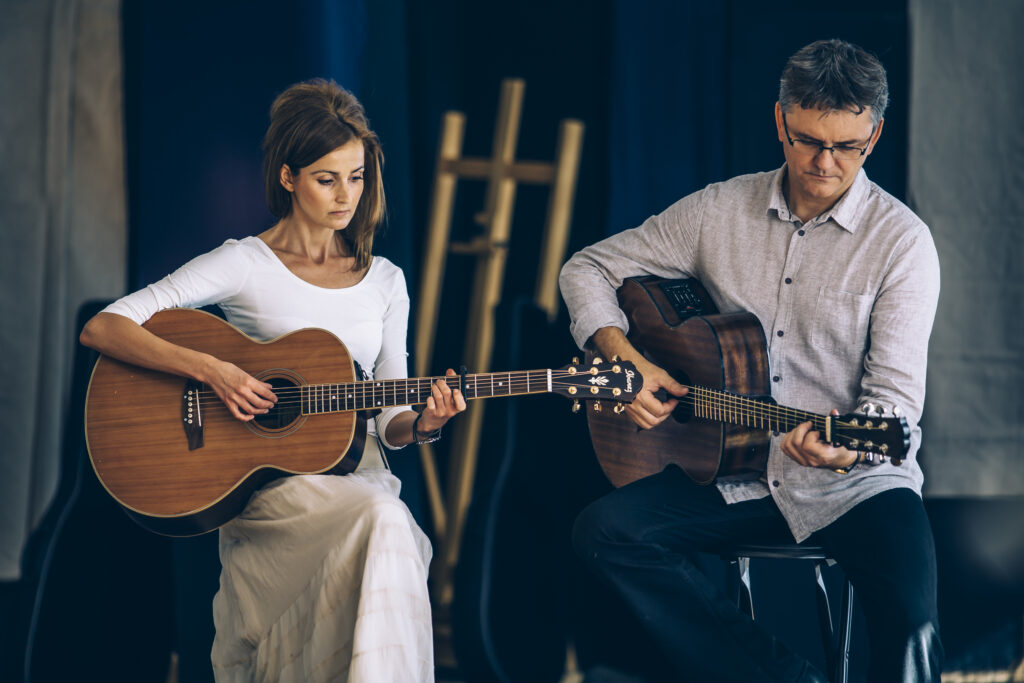 Dwoje muzyków grających na gitarach.