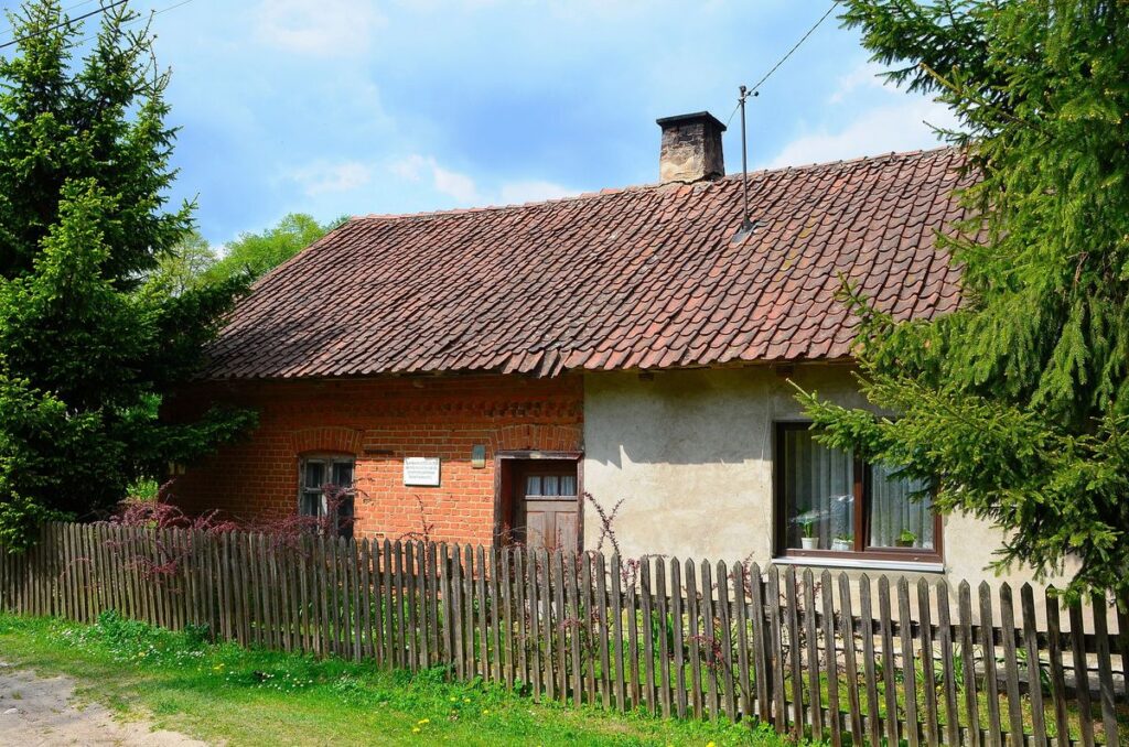 Tradycyjny wiejski domek z ogrodzeniem.