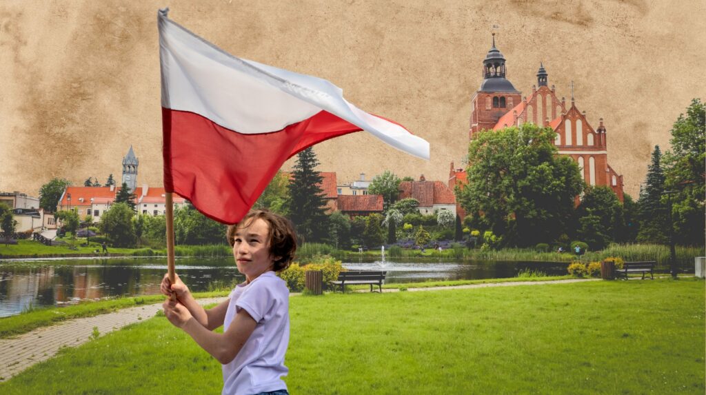 Chłopiec trzymający flagę Polski w parku.