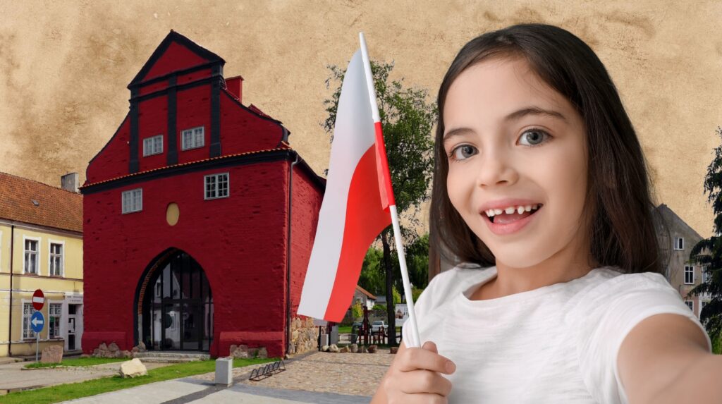 Dziewczynka trzyma flagę Polski przed czerwonym budynkiem.