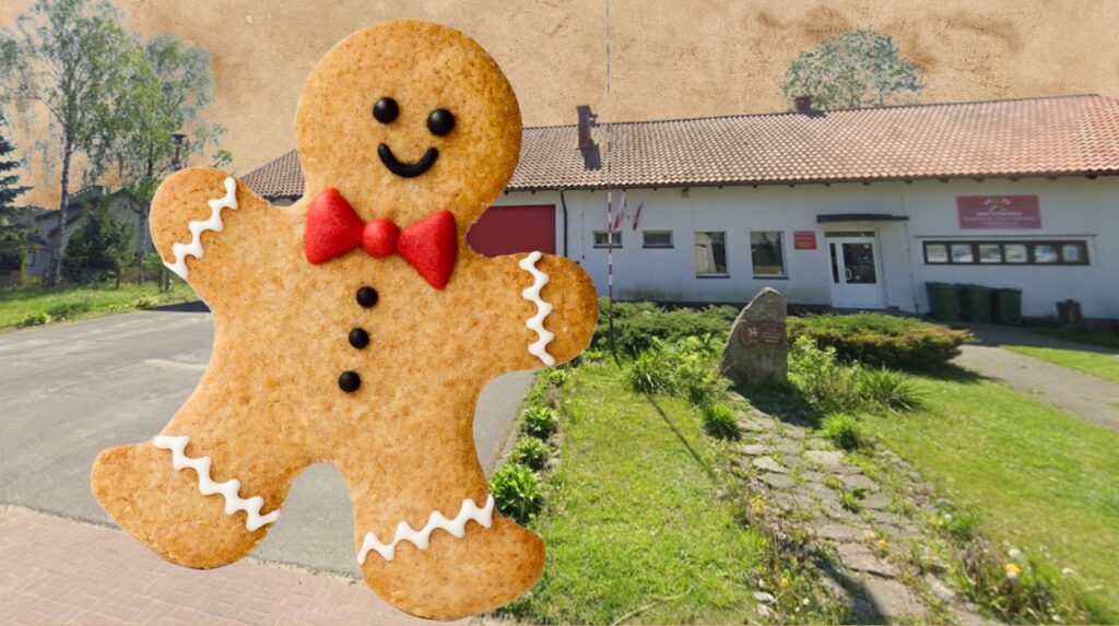 Piernikowy ludzik z budynkiem w tle.