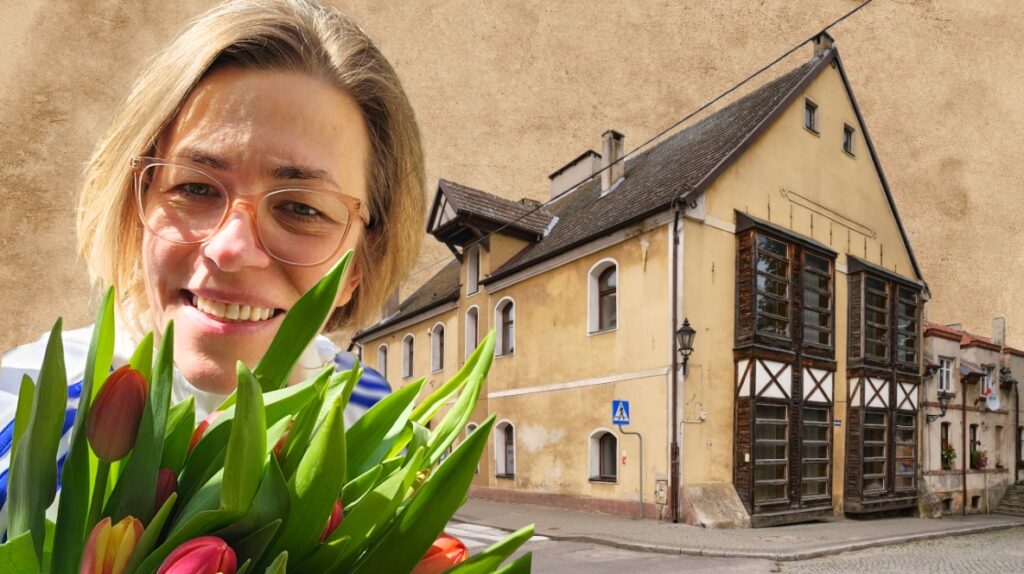 Kobieta z tulipanami przed budynkiem.