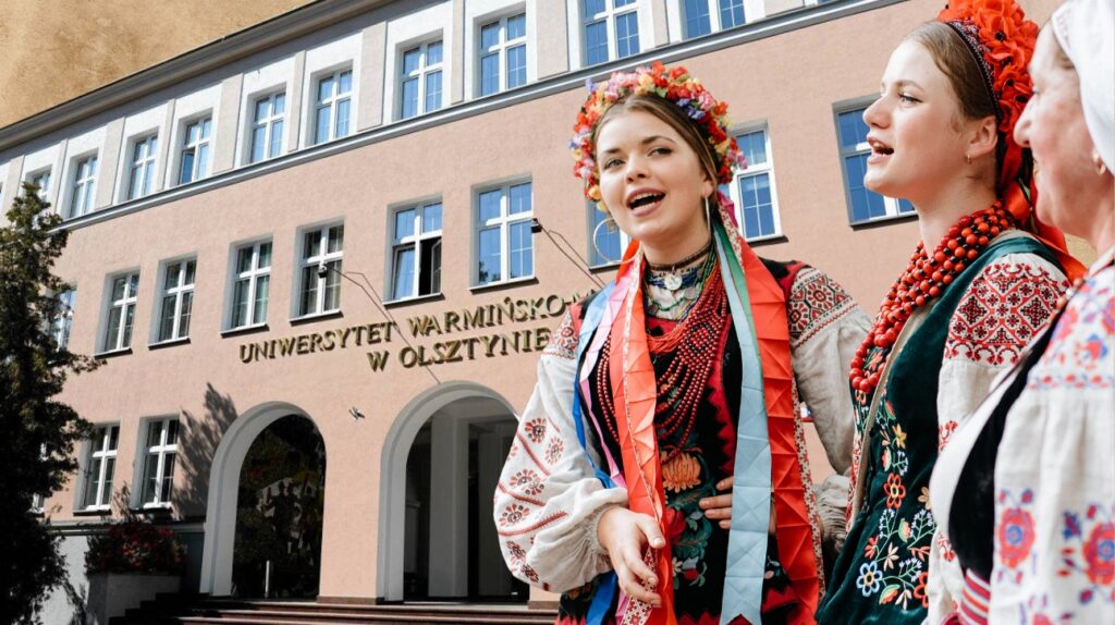 Dwie dziewczyny w tradycyjnych strojach przed budynkiem uczelni