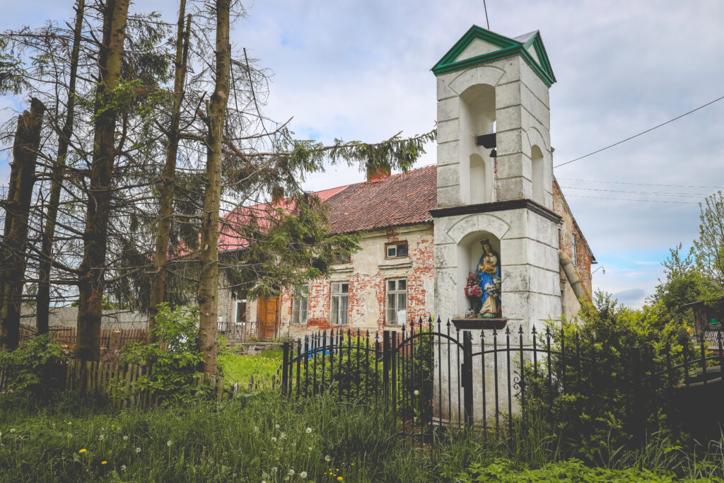 Stara kamienica z dzwonnicą i rzeźbą świętej.