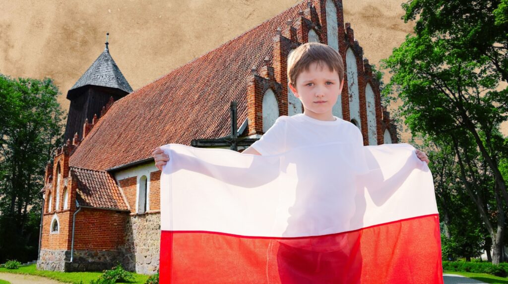 Chłopiec trzyma flagę Polski przed kościołem.