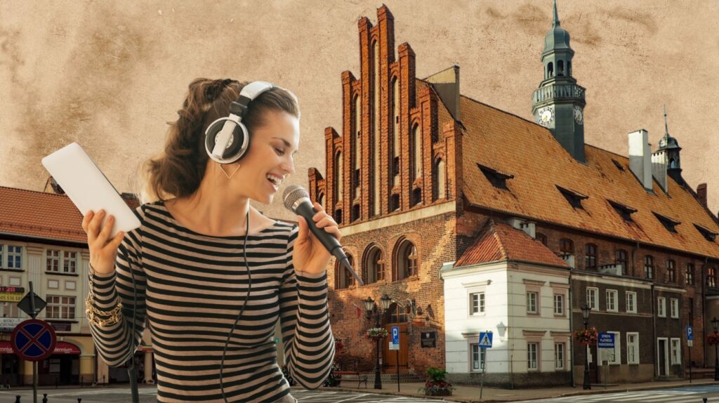 Kobieta w słuchawkach śpiewająca z mikrofonem, z budynkiem w tle.