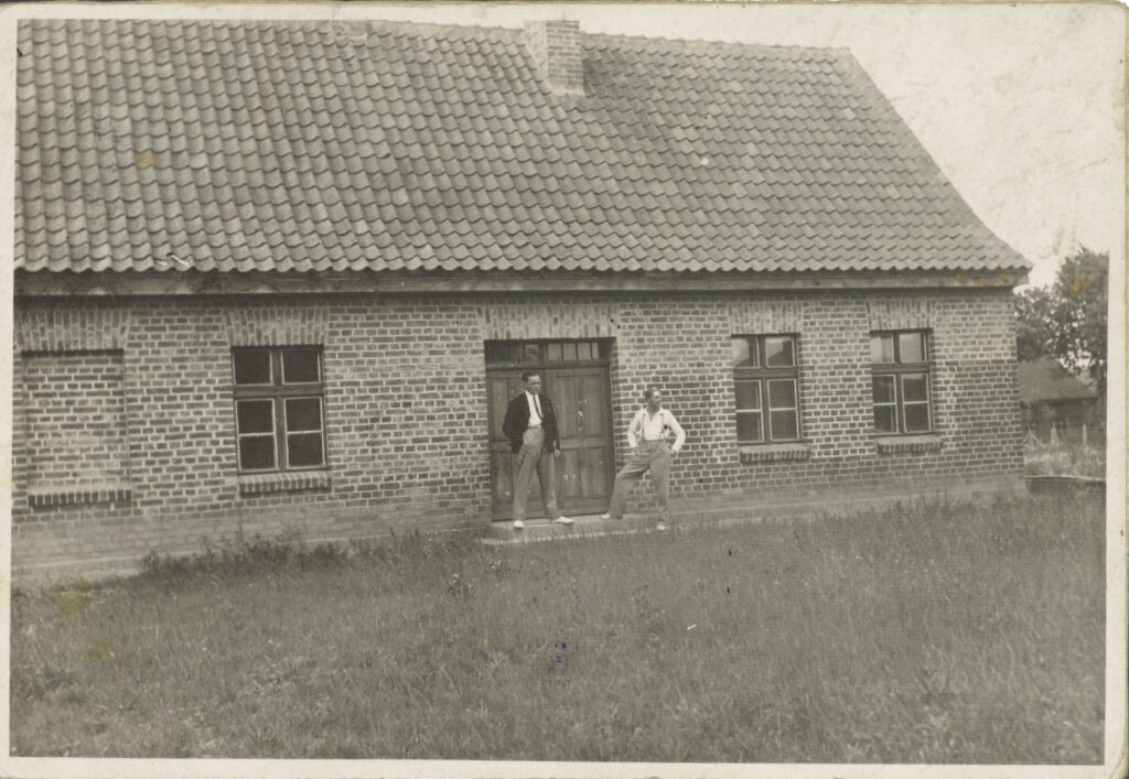 Dwóch mężczyzn stojących przed ceglanym domem.