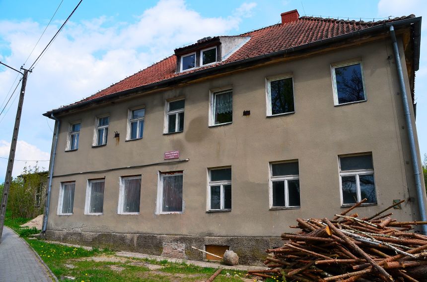 Stary budynek mieszkalny z drewnem na podłożu.