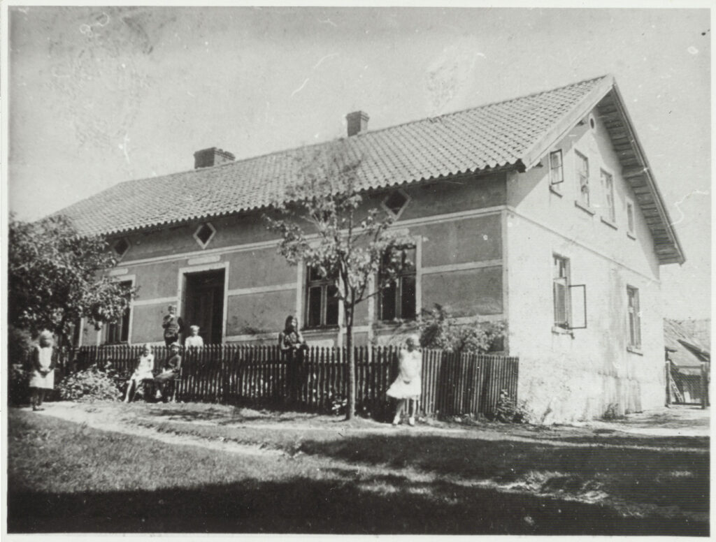 Stara wiejska chata z dziećmi na podwórku.