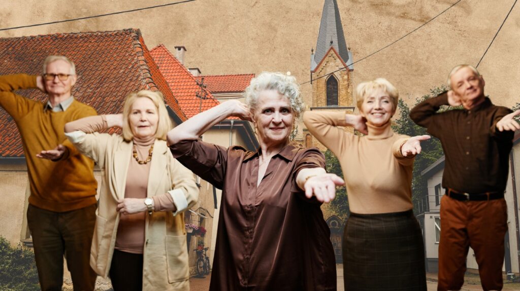 Grupa starszych ludzi pozujących na tle wiejskich domów.