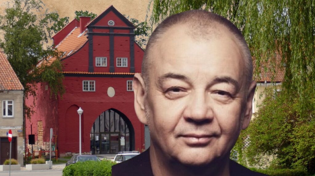 Mężczyzna na tle czerwonego budynku.