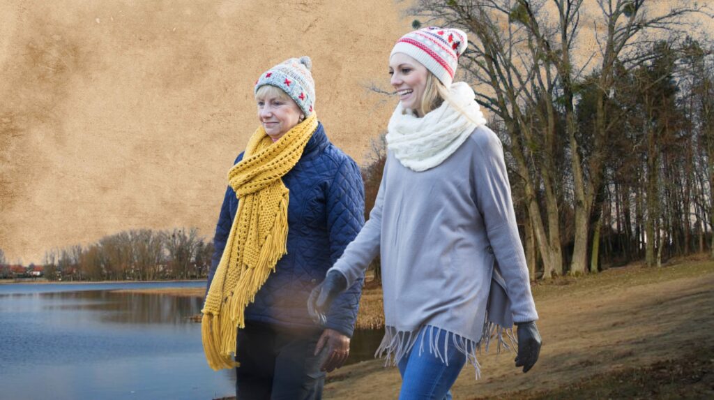 Dwie kobiety spacerują nad jeziorem w zimowej odzieży.