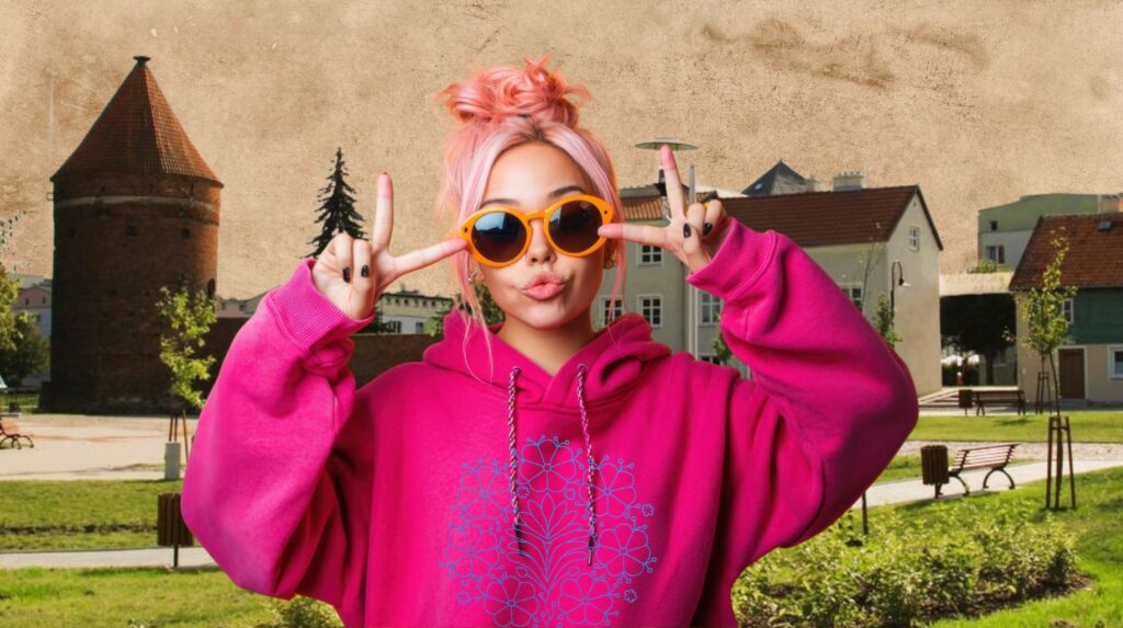 Młoda kobieta w różowej bluzie z okularami przeciwsłonecznymi w parku.