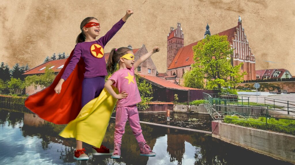 Dwie dziewczynki w superbohaterskich strojach na tle miasta.