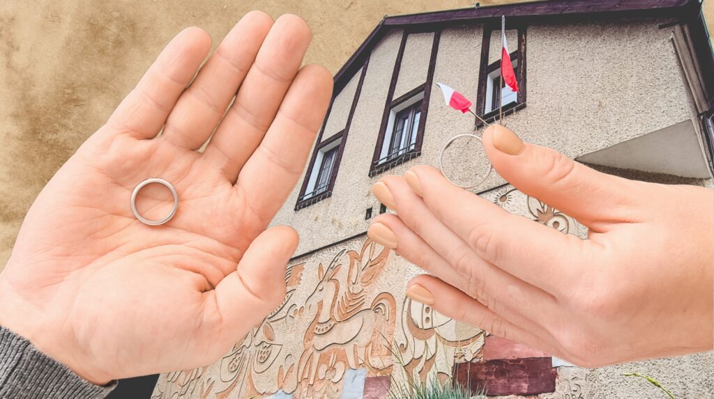 Dwie ręce trzymają obrączkę w tle z muralem.