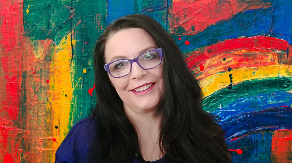 Kobieta z długimi włosami na tle kolorowego obrazu.