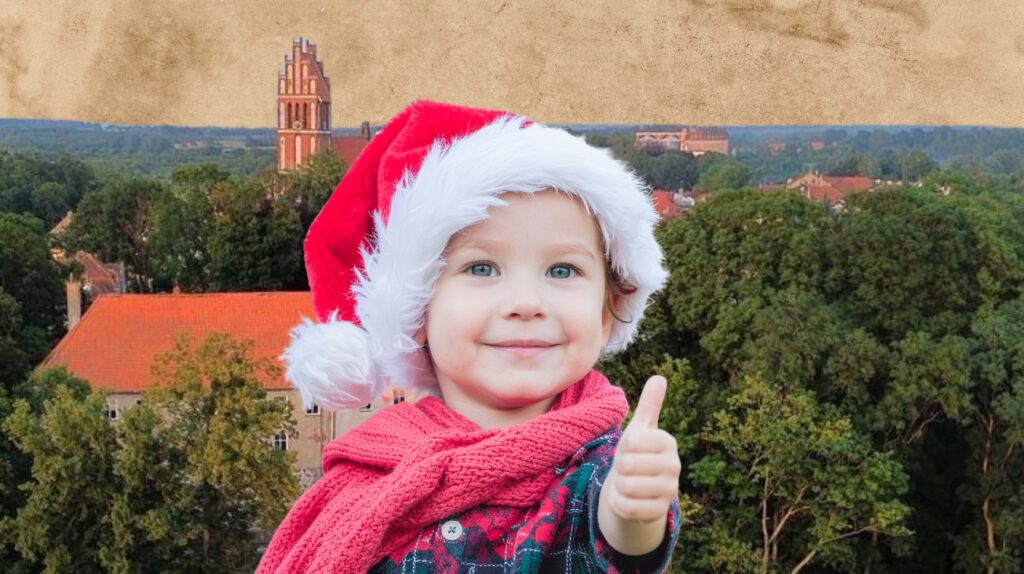 Uśmiechnięte dziecko w czapce Mikołaja z kciukiem w górze.