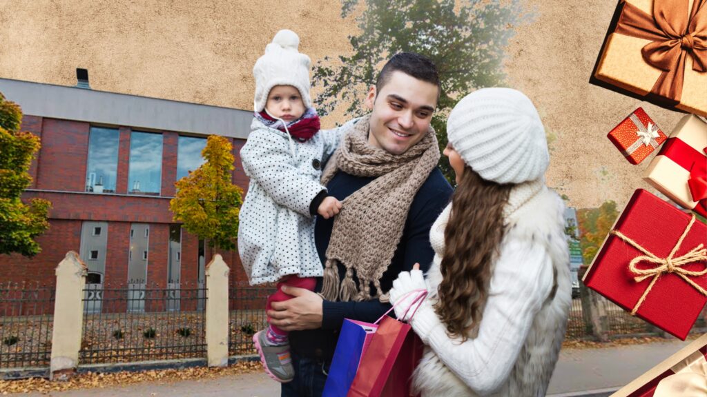 Rodzina na zewnątrz, ojciec trzyma dziecko, matka z torbami zakupowymi.