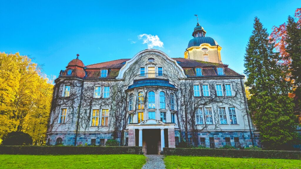 Zabytkowy budynek otoczony drzewami.