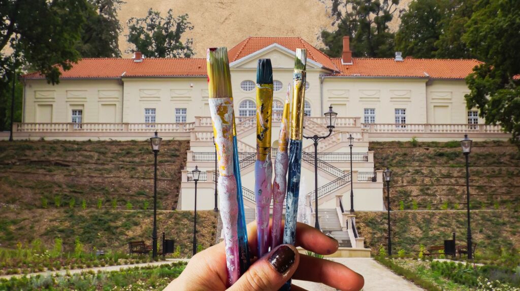 Pędzle trzymane w ręce przed eleganckim budynkiem.