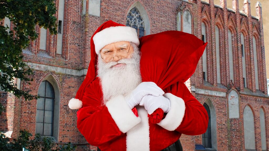 Święty Mikołaj z workiem na tle budynku.