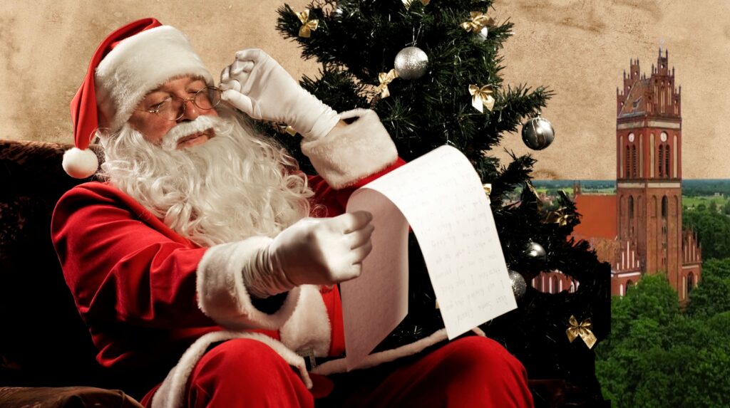 Święty Mikołaj czyta list przy choince.