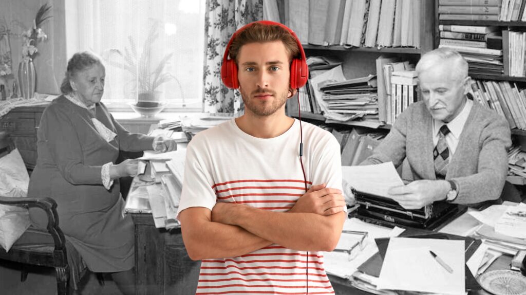 Młody mężczyzna w słuchawkach z widokiem na starsze osoby przy biurku.