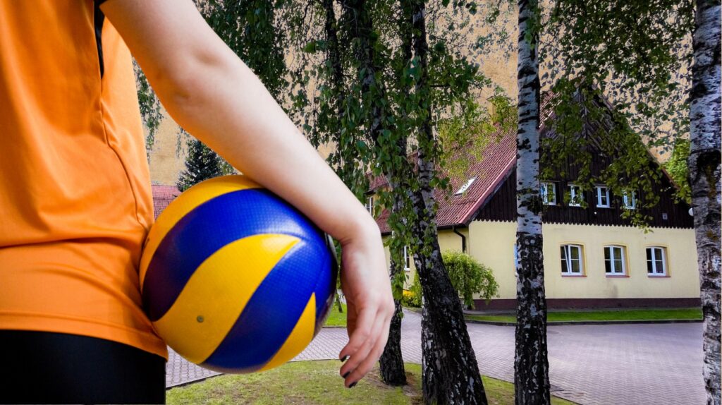 Osoba trzymająca piłkę siatkową w stroju sportowym.