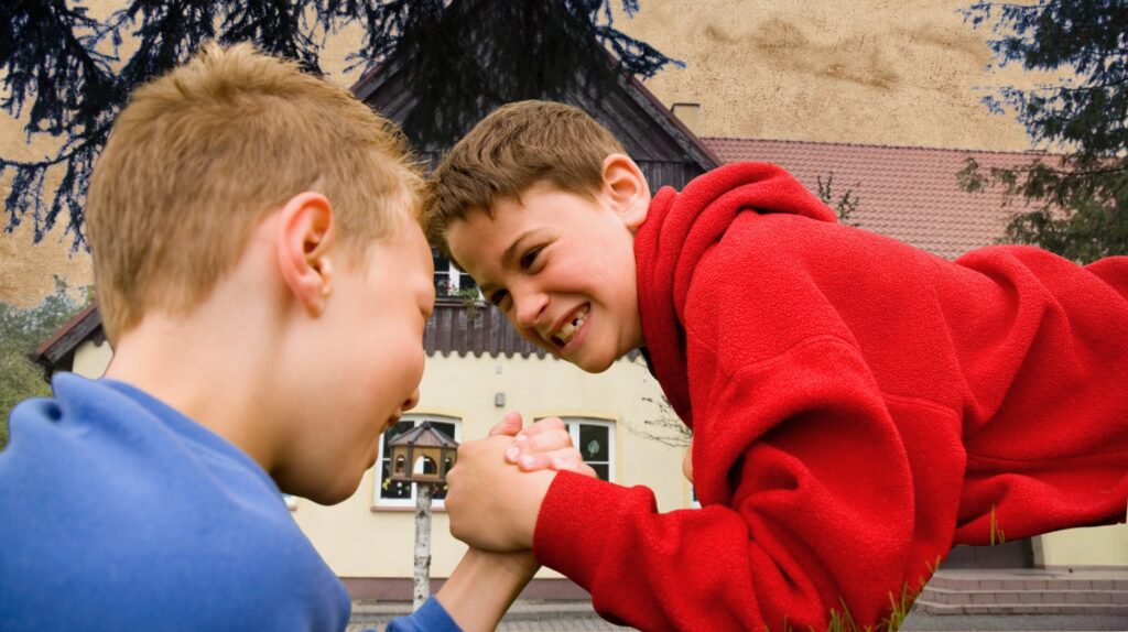 Dwóch chłopców walczy w arm wrestle.