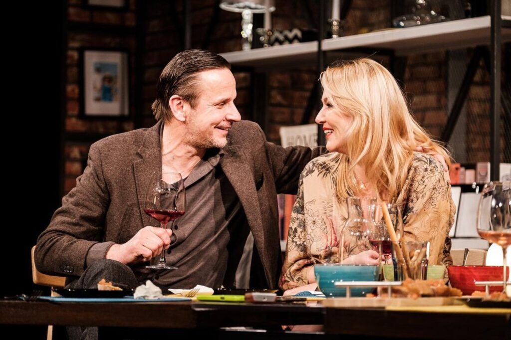 Uśmiechnięta para siedzi przy stole, pijąc wino.