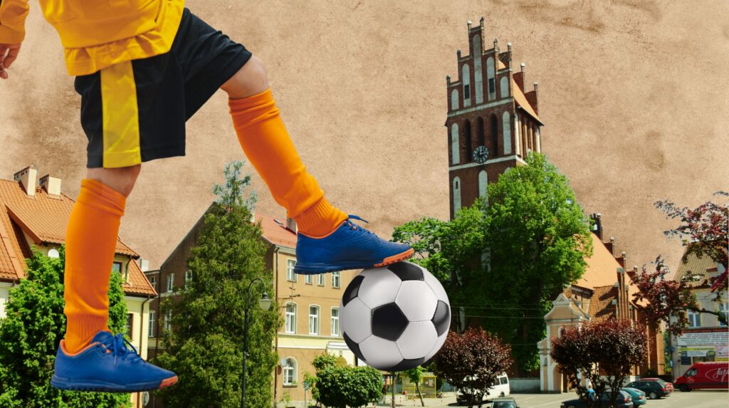 Dziecko gra w piłkę nożną na tle miejskiego krajobrazu.